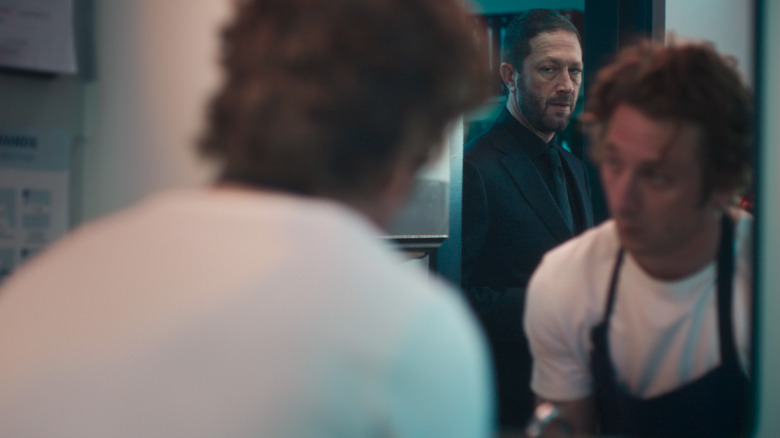 Richie regarde Carmy, qui regarde Richie reflétée dans un miroir dans l'ours de la saison 4