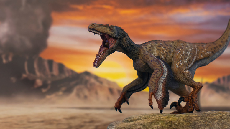 Un Velociraptor à plumes se tient avec sa bouche ouverte avec un volcan en arrière-plan