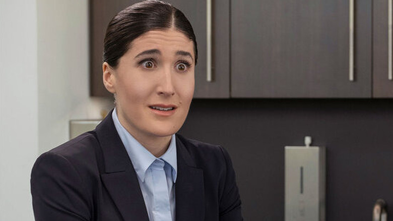 Janelle avec ses cheveux tirés en arrière parlant sur poncédé