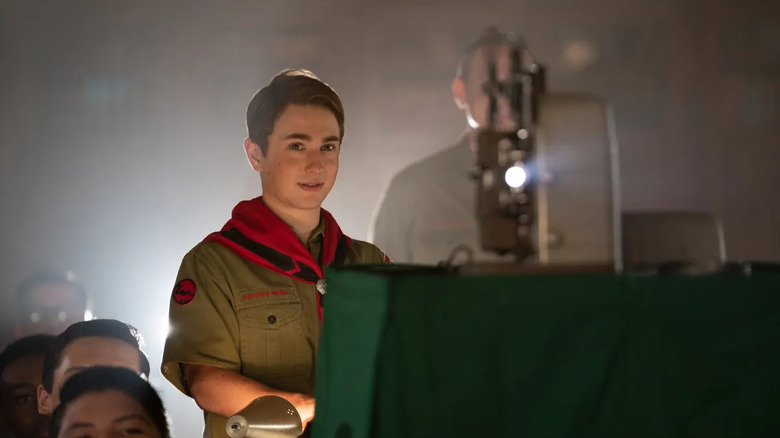 Sammy Fileman regarde son film projeté pour sa classe alors qu'il était vêtu de son uniforme de Boy Scouts dans les Filemans