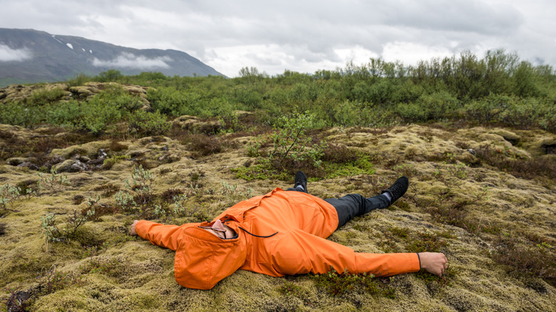 Un randonneur épuisé gise sur le dos un jour humide nuageux