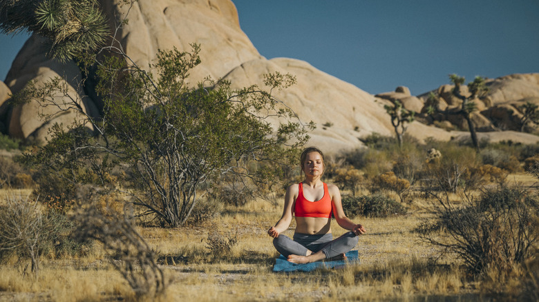 Une jeune femme médite dans le désert