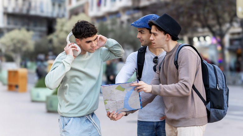 Deux touristes masculins tenant une carte demandant des directions