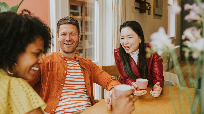 Deux femmes et un homme discutant dans un café