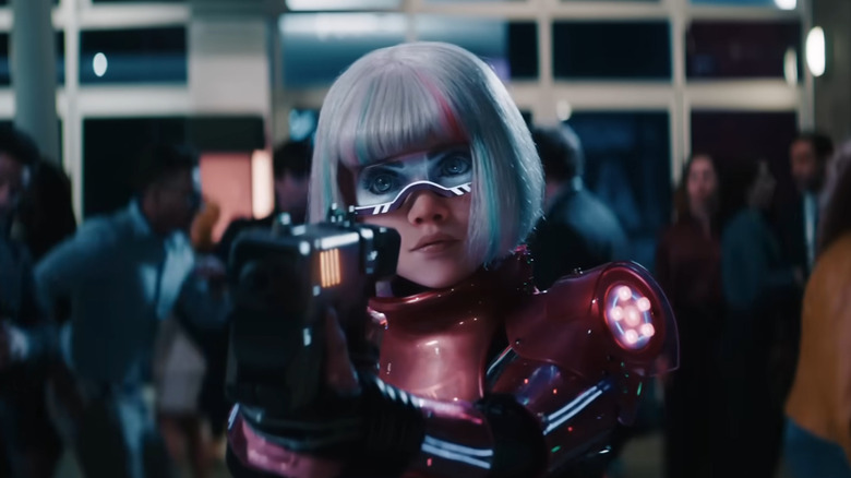 M3gan dans son costume rose tenant un pistolet dans M3gan 2.0