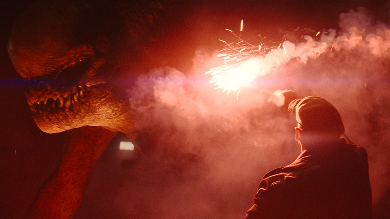 Mahershala Ali en tant que Duncan Kincaid allume une fusée pour distraire un D-Rex dans Jurassic World Rebirth