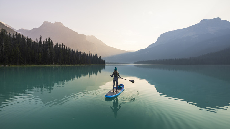 Une femme à pagaie sur un lac immaculé avec des montagnes en arrière-plan