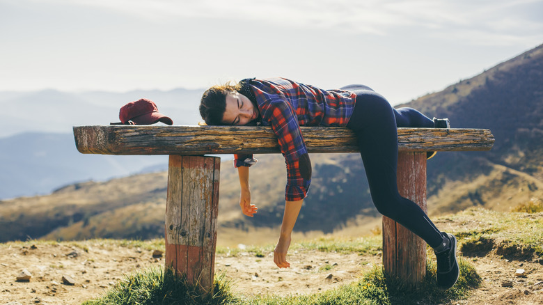La femme complètement fatiguée et usée étend sur le banc lors d'une randonnée
