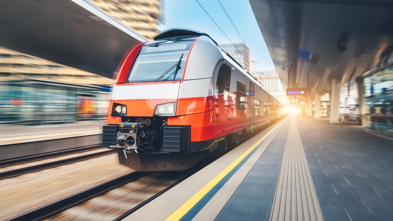 Train orange à grande vitesse traversant la gare