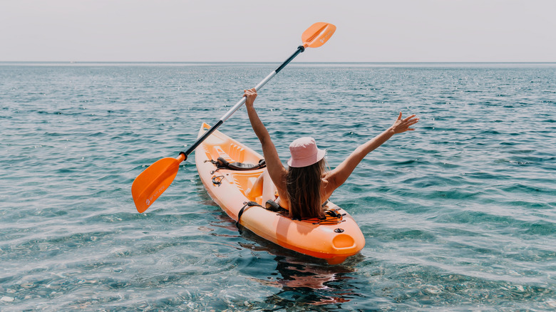 Femme en kayak avec ses bras en l'air