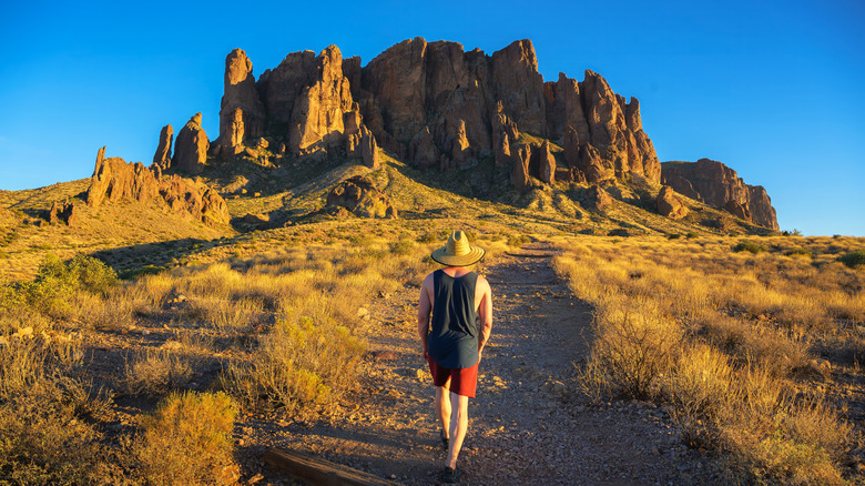 Un randonneur dans un chapeau de paille monte un chemin dans les montagnes de la superstition de l'Arizona