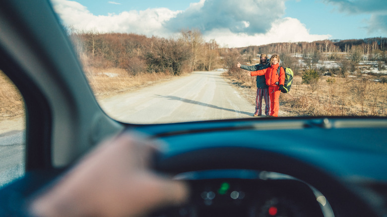 Un couple d'auto-stop attendant que la voiture s'arrête