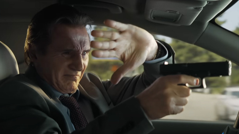 Liam Neeson alors que Frank Drebin tire un pistolet du siège conducteur d'une voiture en conduisant dans le pistolet nu (2025)