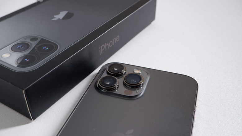 Téléphone mobile avec Apple Brand Iphone 13 Pro Max en graphite et boîte iPhone isolé sur fond blanc.