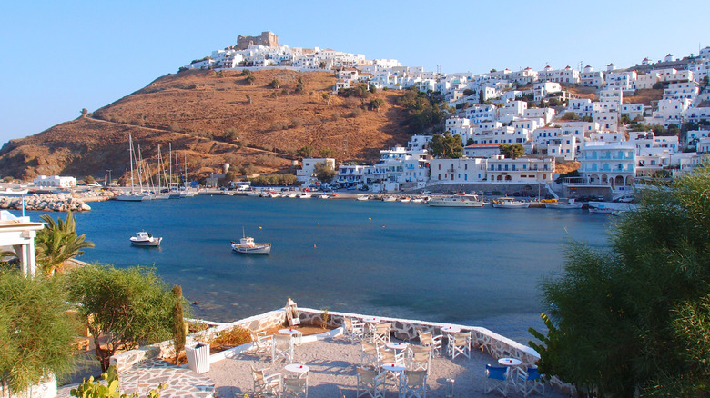 Une baie dans une île grecque avec des tables au premier plan et la Maison Blanche en arrière-plan