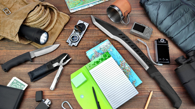 Articles d'équipement de camping sur une table, ainsi que le stylo et le papier.