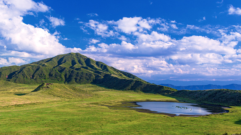Montagnes couvertes par l'herbe avec un petit lac à la base