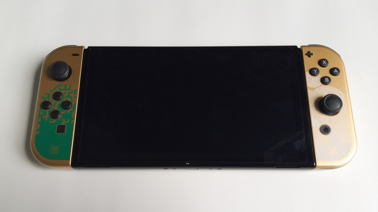 Une légende en édition limitée de Zelda: Larmes of the Kingdom Gold Nintendo Switch Oled Console illustré en mode portable.