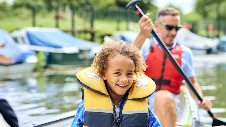 Un père et un enfant dans un canot portant des gilets de sauvetage