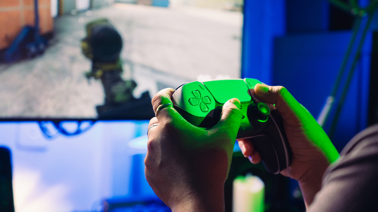 Mains tenant un contrôleur PS5 et jouant au jeu FPS