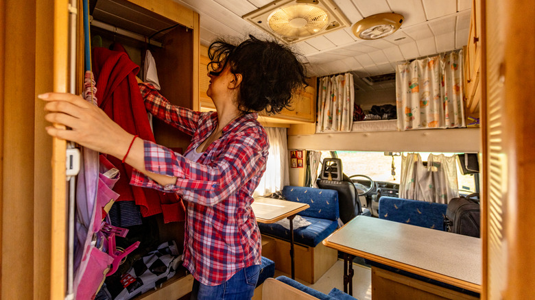 Une personne qui atteint un placard complet de camping-car.