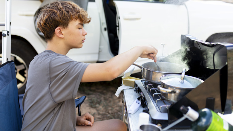 Cuisine d'enfants sur le poêle du camp