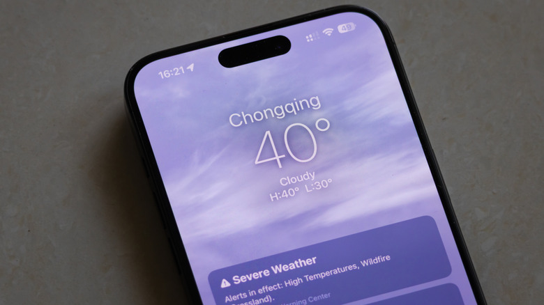 Un smartphone placé sur le sol affiche une application météorologique montrant une température de 40 ° C