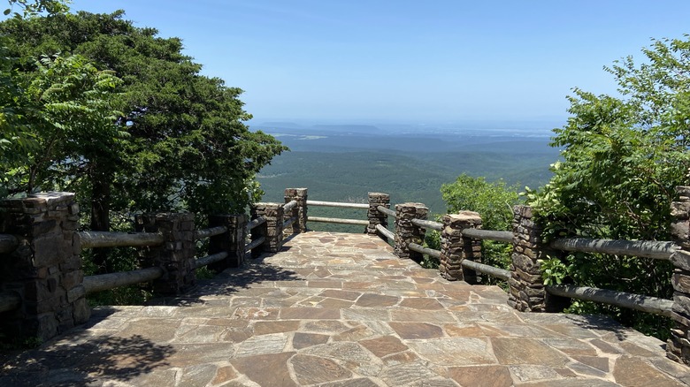 Une passerelle de visiteurs avec une clôture rocheuse et une vue panoramique sur les forêts et les collines