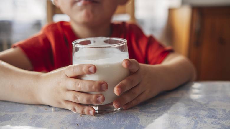 les mains de l'enfant tenant du verre de lait