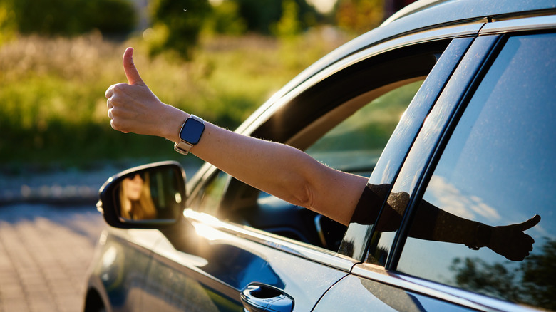 Une personne donnant le coup de pouce par une fenêtre de voiture.