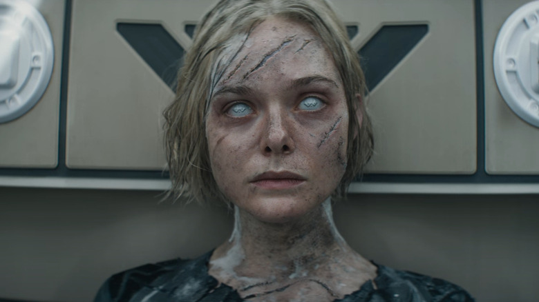Elle fanning comme thia assise dans une chambre battue de la bataille dans Predator: Badlands