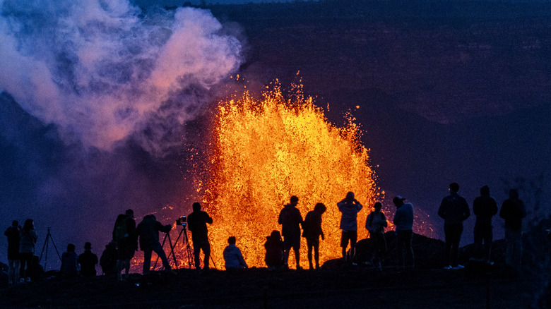 Les gens qui regardent la lave crachent du volcan Kīlauea d'Hawaï en mai 2025