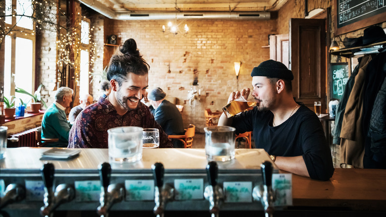 Deux amis qui traînent et buvant dans un bar élégant ensemble