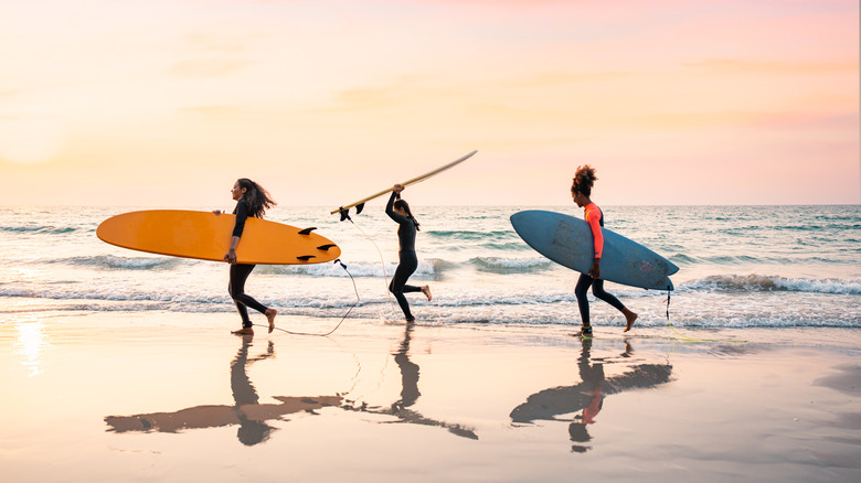 Trois personnes au bord de la mer tenant des planches de surf