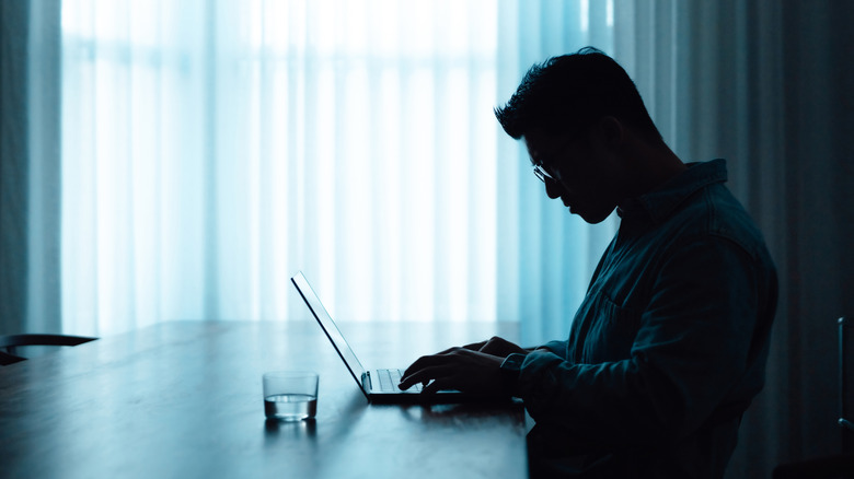 Silhouette Man travaillant sur un ordinateur portable