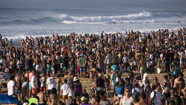 Une foule sur la plage en regardant un concours de surf