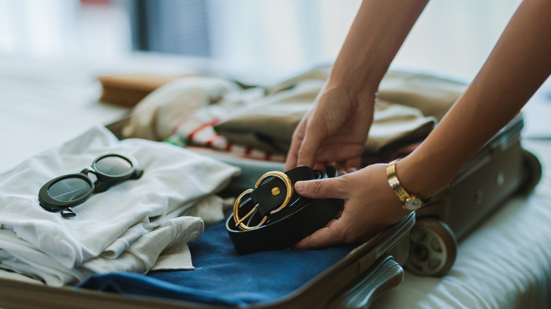 Quelqu'un emballe une valise avec des vêtements
