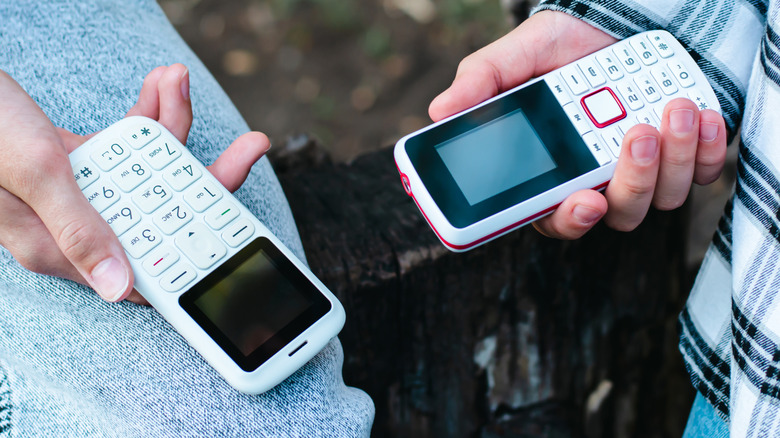 Deux téléphones portables simples qui se tenaient en face de l'autre par deux personnes