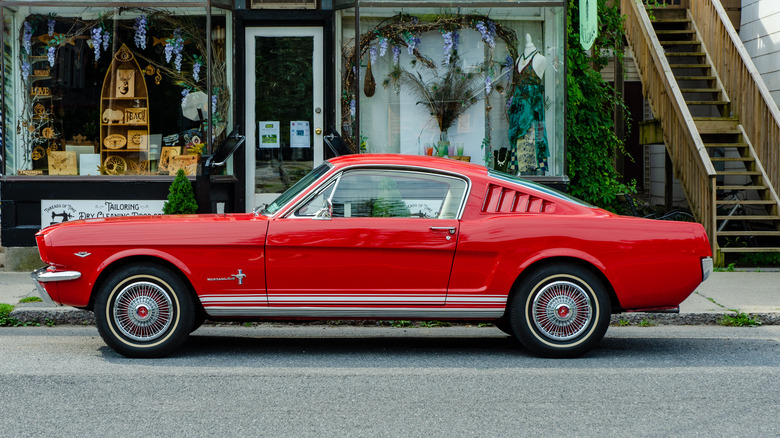 Une mustang rouge vintage se trouve devant une boutique pittoresque à Phenicia, New York