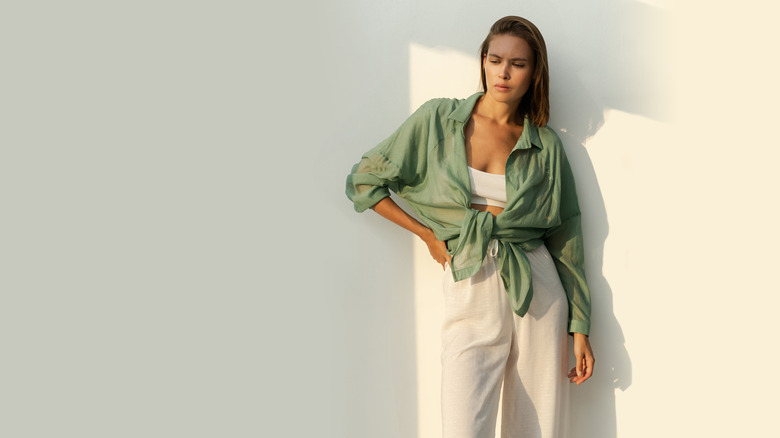 Une femme élégante portant une tenue en lin tout en posant contre un mur