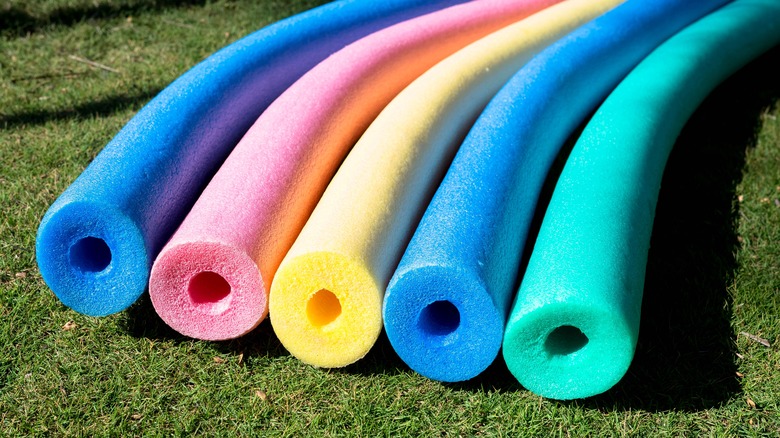Nouilles de piscine dans différentes couleurs allongées sur l'herbe