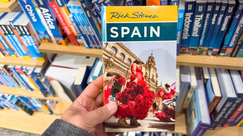 Une vue d'une main tenant un livre de voyage Rick Steves, à la librairie