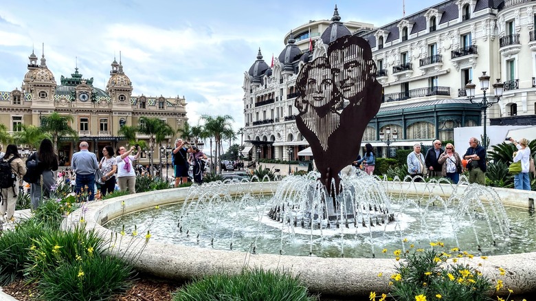 Fontaine avec sculpture, bâtiments ornés, touristes