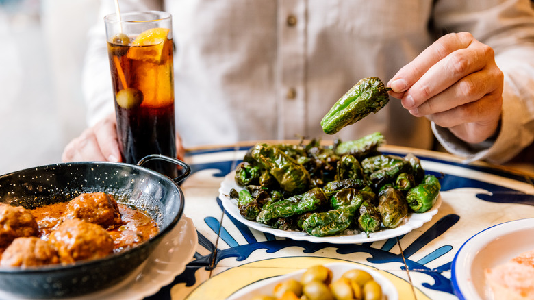 Une table avec des poivrons grillés, des olives, des boulettes de viande espagnols et du vermouth