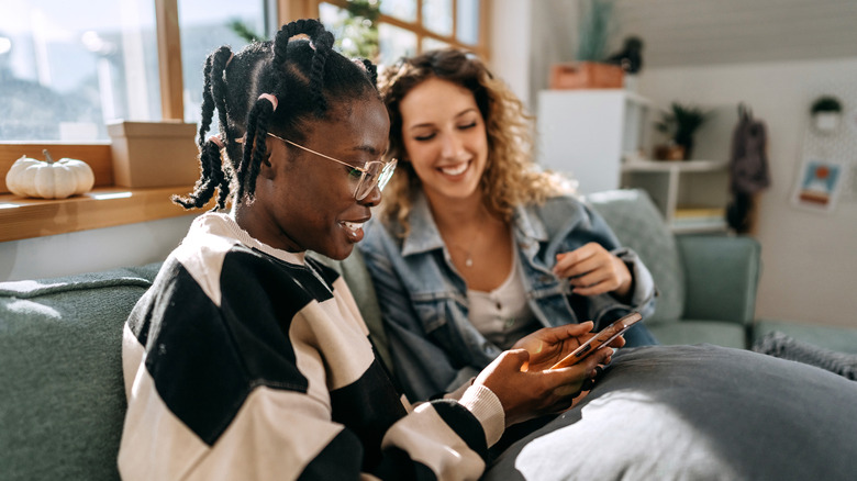Une femme noire et blanche utilisant l'application de rencontres et souriant