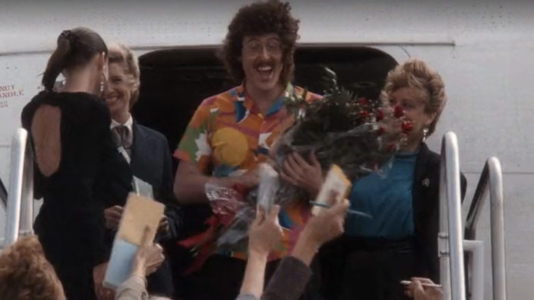 Weird Al Yankovic reçoit des fleurs, une presse et des ventilateurs tout en sortant d'un avion de passagers dans le pistolet nu (1988)