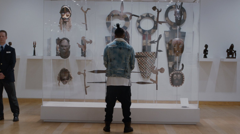 Erik Killmonger (Michael B Jordan) se tient devant un cas d'artefacts à Black Panther