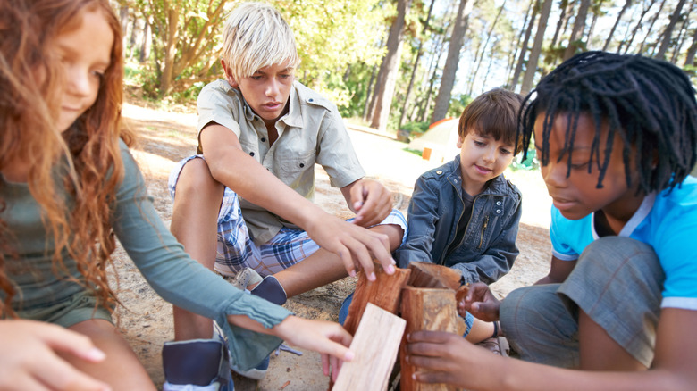 Groupe d'enfants de camp travaille ensemble pour construire un feu