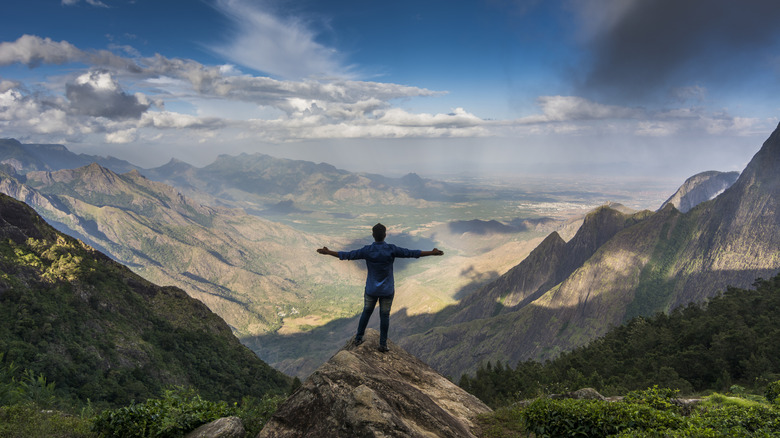 Un homme se tient sur une montagne à Kolukkumalai, en Inde