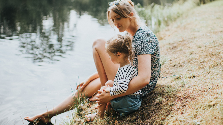 Adulte et enfant assis près du lac